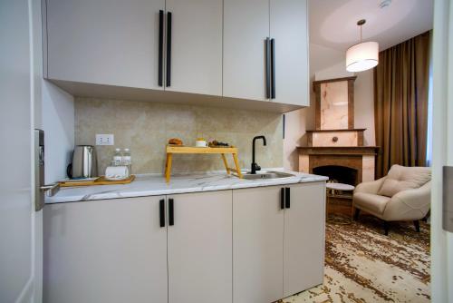 een keuken met witte kasten en een woonkamer bij The House Hotel Yerevan in Jerevan
