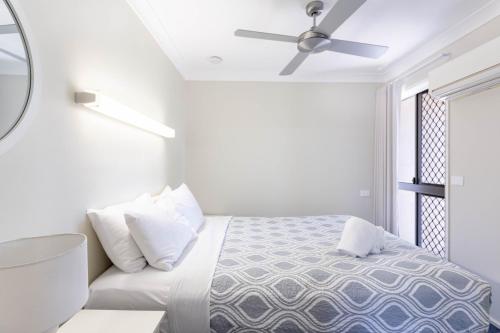 a white bedroom with a bed and a window at Driftwood on the Beach in Yeppoon