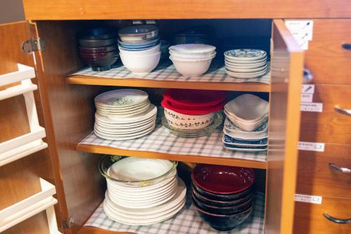 a cabinet filled with plates and bowls on shelves at 千葉の静かな山の中の貸切コテージ 鴨川コテージ in Kamogawa