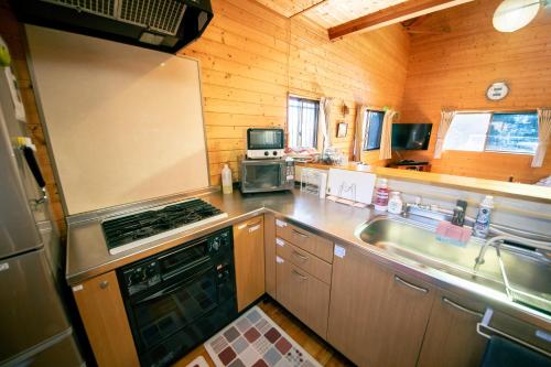 a kitchen with a sink and a stove top oven at 千葉の静かな山の中の貸切コテージ 鴨川コテージ in Kamogawa
