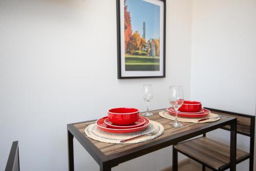 - une table avec des assiettes rouges et des verres à vin dans l'établissement Te alojo Conce, Apart Hotel, à Concepción