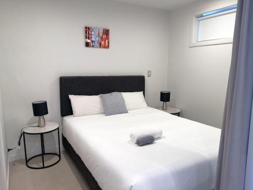 ein Schlafzimmer mit einem großen weißen Bett mit zwei Lampen in der Unterkunft Modern 2 Bedroom Apartment 1 minute to Skytower in Auckland