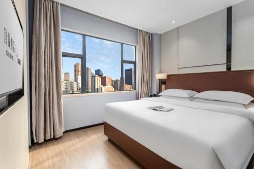 Cette chambre comprend un lit et une grande fenêtre. dans l'établissement YZHI Hotel - Guangzhou Panyu City Bridge Subway Station, à Canton