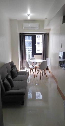 uma sala de estar com um sofá, uma mesa e cadeiras em JM Suite at LovetoStay em Manila