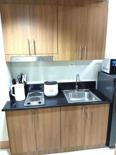 um balcão de cozinha com um lavatório e um fogão em JM Suite at LovetoStay em Manila