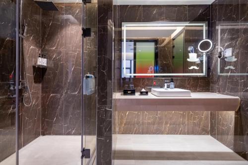 uma casa de banho com um lavatório e um espelho em YZHI Hotel - Guangzhou Panyu City Bridge Subway Station em Guangzhou