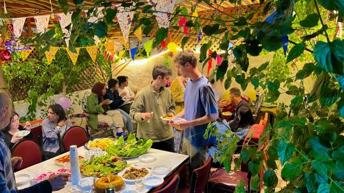 un grupo de personas de pie alrededor de una mesa con comida en Al-Amer Hostel 1, en Áqaba