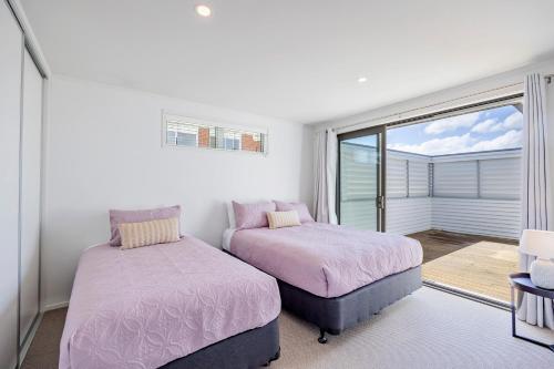 a bedroom with two beds and a balcony at White Beauty in Auckland