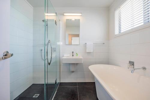 a bathroom with a shower and a sink and a bath tub at White Beauty in Auckland
