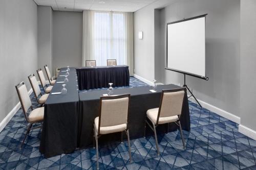 a conference room with a table and chairs and a screen at Courtyard Shelton in Shelton