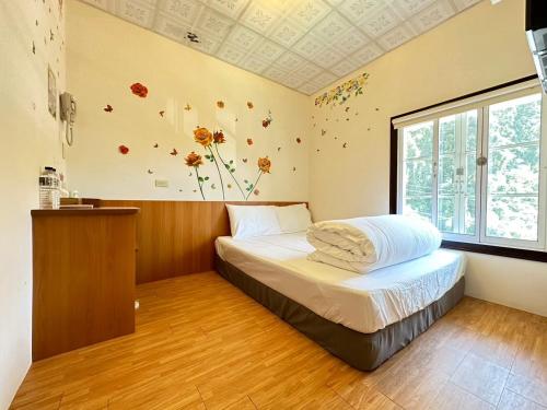 a bedroom with a bed with flowers on the wall at Deep Forest Inn in Fenchihu