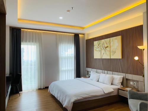 a bedroom with a large white bed and a desk at Sinergi Hotel & Villa in Sengkaling