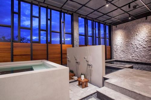 a bathroom with a bath tub and a large window at Balcony Seaside Sriracha Hotel & Serviced Apartments in Si Racha
