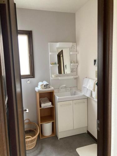 a white bathroom with a sink and a mirror at Maison Petit Lapin メゾンプチラパン in Karuizawa