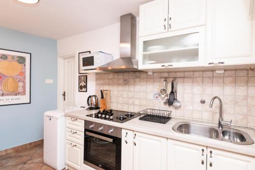 a kitchen with white cabinets and a sink at Kontra Split in Split