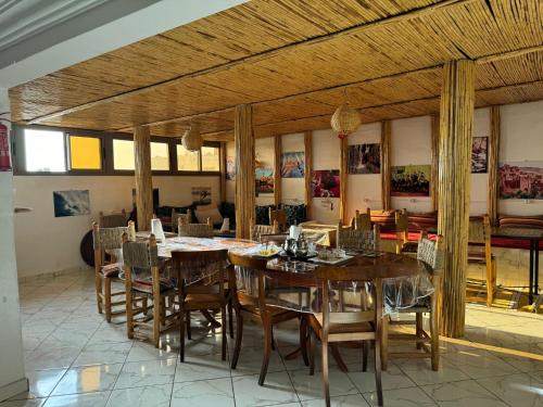 una sala da pranzo con tavoli e sedie in legno di Dinosaur Anza Surf House ad Agadir