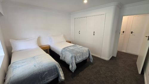 a bedroom with two beds and a closet and a bedskirts at Grandpa’s Place in Te Aroha
