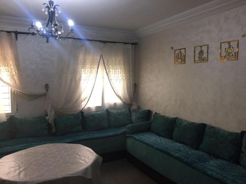a living room with a green couch and a window at apparemment à louer pour les familles in Meknès