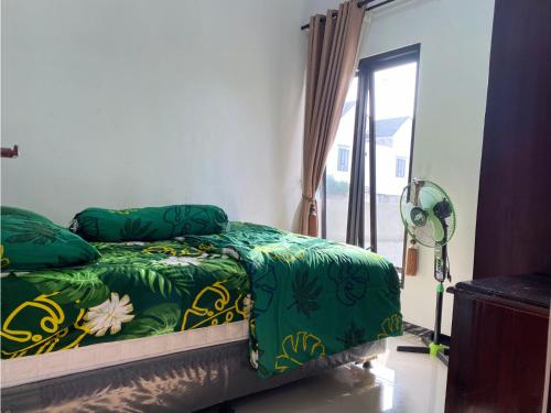 a bedroom with a bed with green sheets and a window at Villa Harga Terjangkau di Malang in Malang