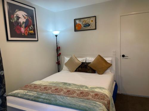 una camera da letto con un letto bianco e cuscini sopra di Auckland CBD, Parnell Ensuite+Patio+Secluded Garage ad Auckland