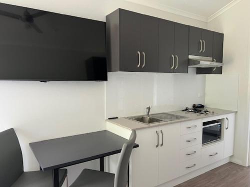 a kitchen with black and white cabinets and a sink at Denman Van Village in Denman