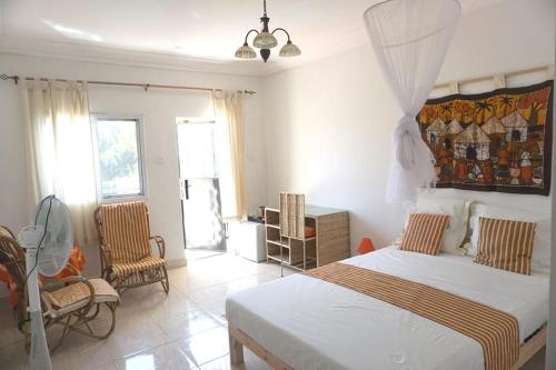 a bedroom with a bed and two chairs in it at Kukunjang in Banjul