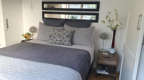 a bedroom with a bed with a gray comforter and a window at The Cube in Martinborough