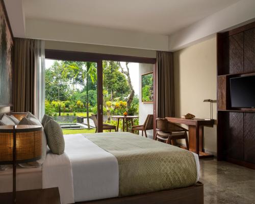 a bedroom with a bed and a sliding glass door at Adiwana Suweta in Ubud