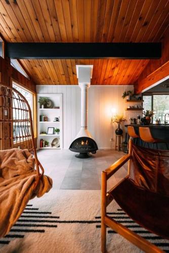 a living room with a fireplace in the middle of a room at Mid-Century Cabin Perfect for Romantic Getaway in Running Springs