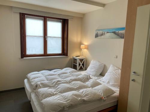 een groot wit bed in een kamer met een raam bij Zonnehaven III 64B with a central location in Nieuwpoort