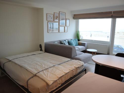 ein Wohnzimmer mit einem Bett und einem Sofa in der Unterkunft Riva Bella 102 right on the beach in Nieuwpoort