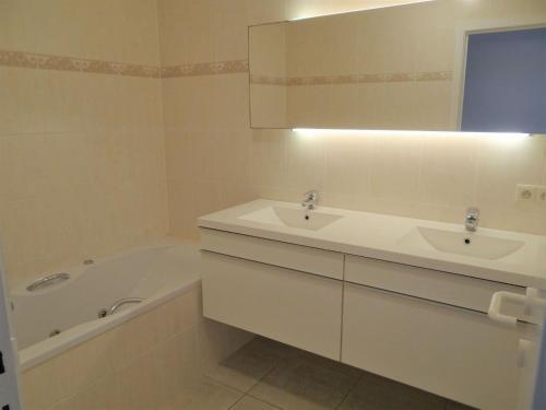 a bathroom with a sink and a tub and a mirror at Apartment Sea View 0604 with top location in Nieuwpoort