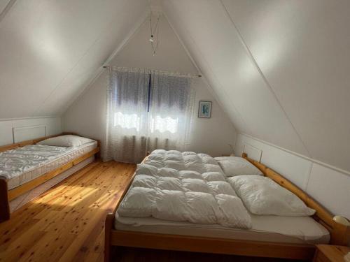 2 Betten in einem Schlafzimmer im Dachgeschoss mit Fenster in der Unterkunft Holiday home Watersnip 5 in Lemmer