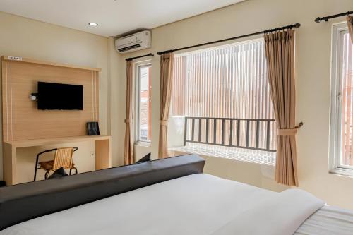 a bedroom with a bed and a tv and a window at Super OYO Airport Kuta Bali Hotel in Kuta
