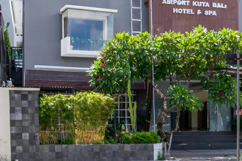 un edificio con árboles y arbustos delante de él en Super OYO 93765 Airport Kuta Bali Hotel en Kuta