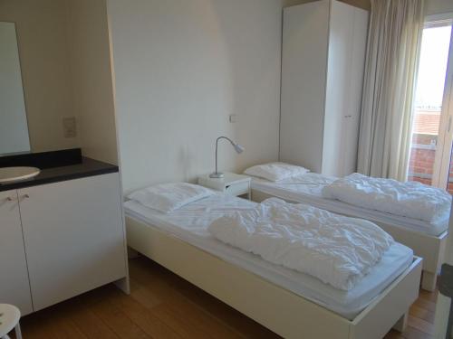 2 camas en una habitación blanca con ventana en Ibiza 701 with frontal sea view, en Nieuwpoort