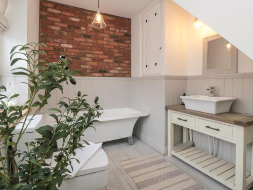 a bathroom with a white sink and a brick wall at Harriet's Cottage in Whitby