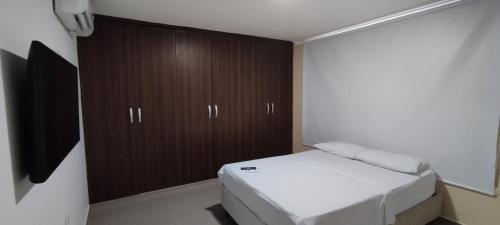 Dormitorio pequeño con cama y armarios de madera en Hermosa casa amoblada, en Barranquilla