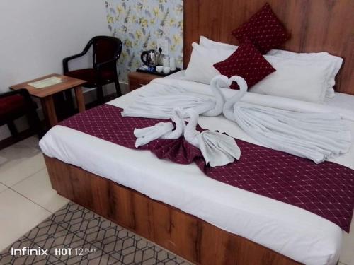 Una cama con toallas blancas encima. en Hotel Shiwalik Enclave en Baddi