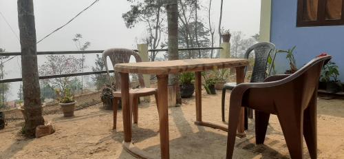 uma mesa de madeira e cadeiras sentadas numa varanda em Aarav Homestay em Kalimpong
