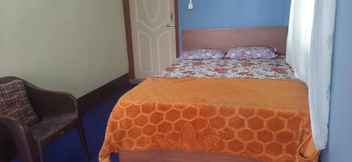 uma pequena cama num quarto com uma colcha laranja em Aarav Homestay em Kalimpong