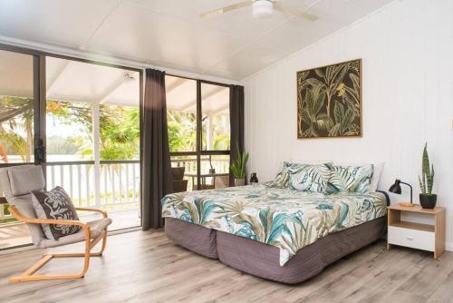 a bedroom with a bed and a chair at B's Beach House on Muri Lagoon in Rarotonga