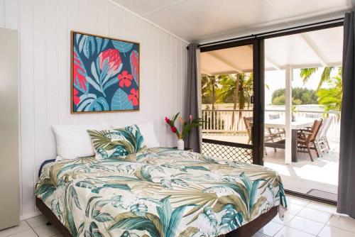 a bedroom with a bed and a patio with a table at B's Beach House on Muri Lagoon in Rarotonga