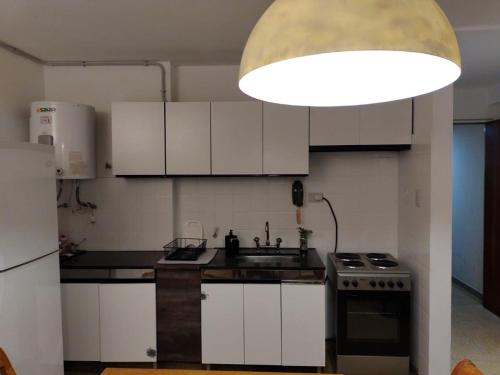 eine Küche mit weißen Schränken, einer Spüle und einer Lampe in der Unterkunft Depa 900 cómodo remodelado centro cerca de todo in Cordoba