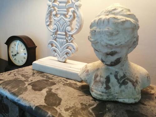 a statue of a bust next to a clock at La maison O kiwis - Chambres d'hôtes in Saint-Denis-lès-Martel