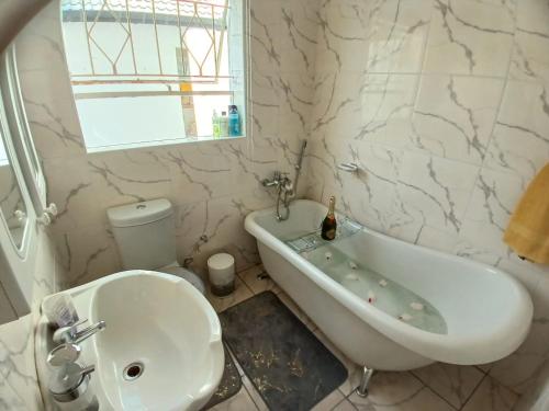 a white bathroom with a tub and a sink at Sbukosezwe guest house in Johannesburg