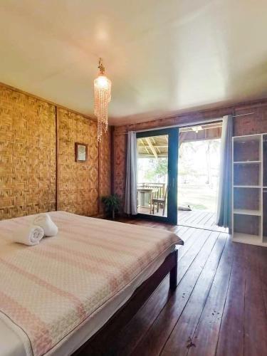 a bedroom with a large bed and a chandelier at Family Cabana at Amihan Surf Cabanas in General Luna