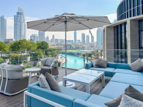 a patio with blue couches and an umbrella at Address Opera Residences Burj Khalifa View in Dubai