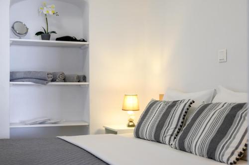 a white bedroom with a bed with a lamp and shelves at Marillia's elegance residence in Mesaria