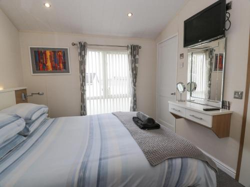 a bedroom with a large bed with a television on the wall at Oyster Bay Lodge in Dalbeattie